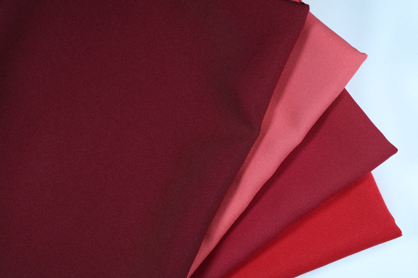 Polyester Panama Stoffe in Rot- und Violetttönen – nebeneinandergelegt von Weinrot über Hellrot bis hin zu strukturiertem Rot für elegante Farbvergleiche bei Dekostoffen