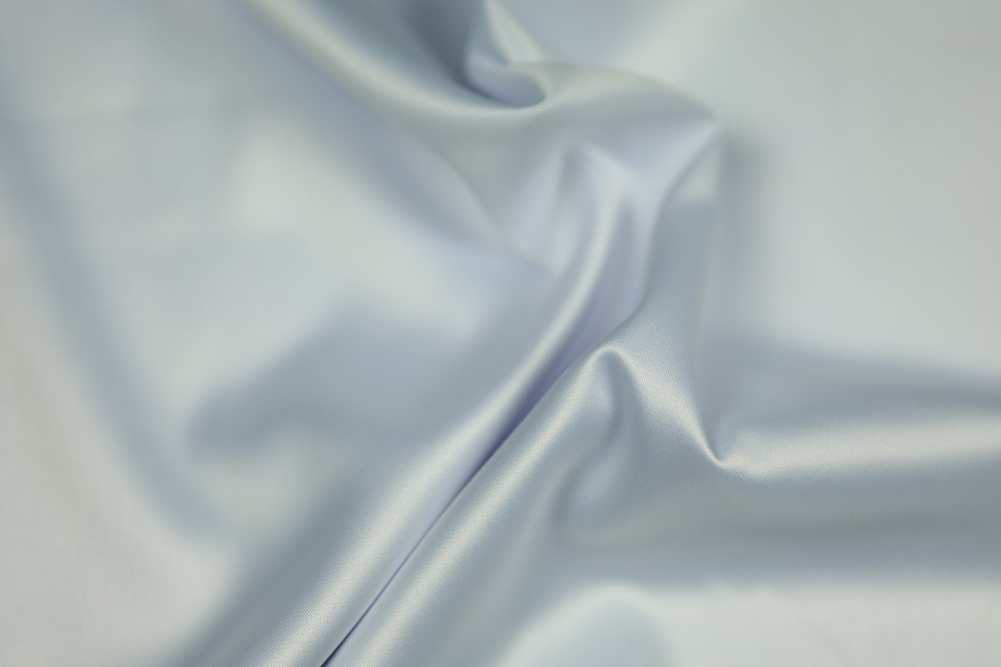 Satinstoff in zartem Eisblau mit seidig glänzender Oberfläche und fließender Drapierung – perfekt für festliche Kleidung und elegante Dekorationen